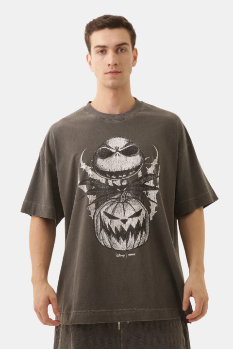 Modelo masculino usando uma camiseta oversized inspirada em O Estranho Mundo de Jack, com estampa de Jack Skellington e abóboras.