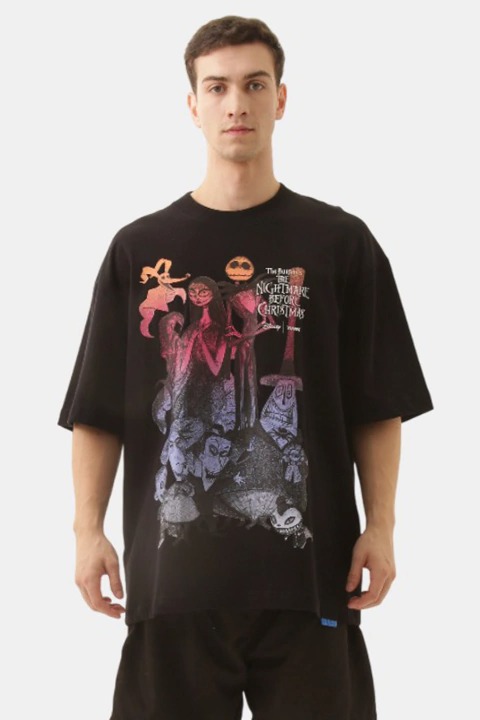 Modelo masculino vestindo uma camiseta oversized preta com estampa colorida de personagens do filme 'O Estranho Mundo de Jack'.