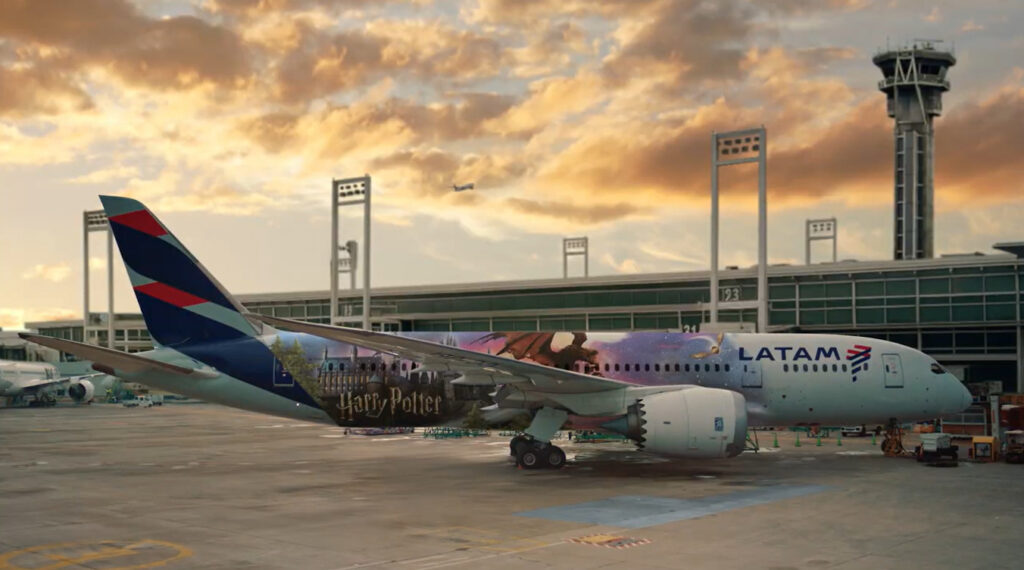 Aeronave da LATAM inspirada em Harry Potter estacionada no aeroporto, exibindo um design especial com ilustrações do universo mágico.
