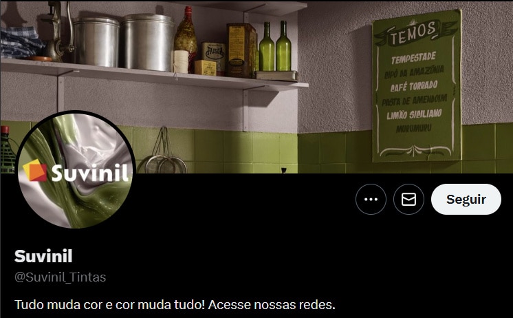 Imagem do perfil do Twitter da Suvinil, com a logo da marca e um background que mostra prateleiras de cozinha com produtos e uma parede verde, além de um quadro com as cores do ano 2026.