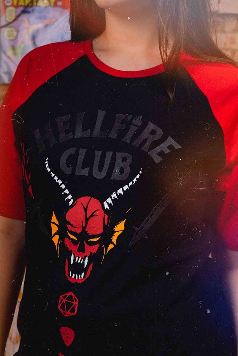 Modelo usando camiseta do Hellfire Club com estampa de um demônio em fundo preto e mangas vermelhas.