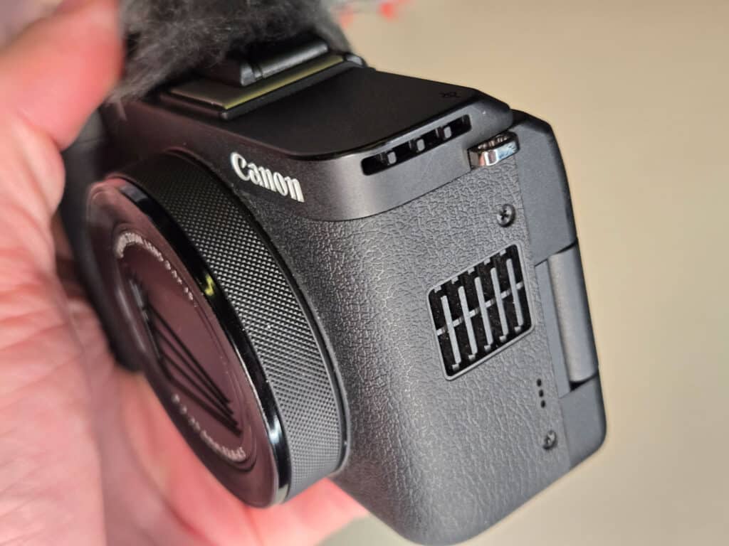 Close-up da Canon PowerShot V1, mostrando o design compacto, a lente e as entradas de ventilação.