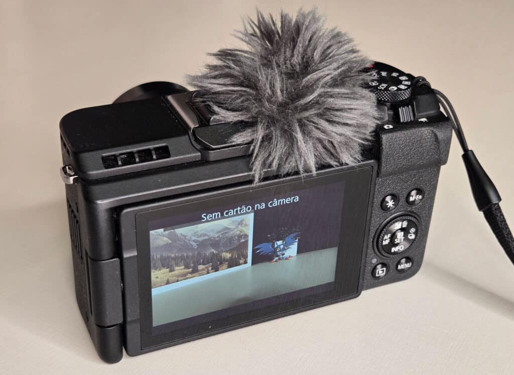 Imagem mostrando a parte traseira da Canon PowerShot V1 com um microfone de pelúcia instalado e a tela exibindo a mensagem 'Sem cartão na câmera'.