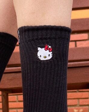 Meia preta com bordado da personagem Hello Kitty na parte superior.