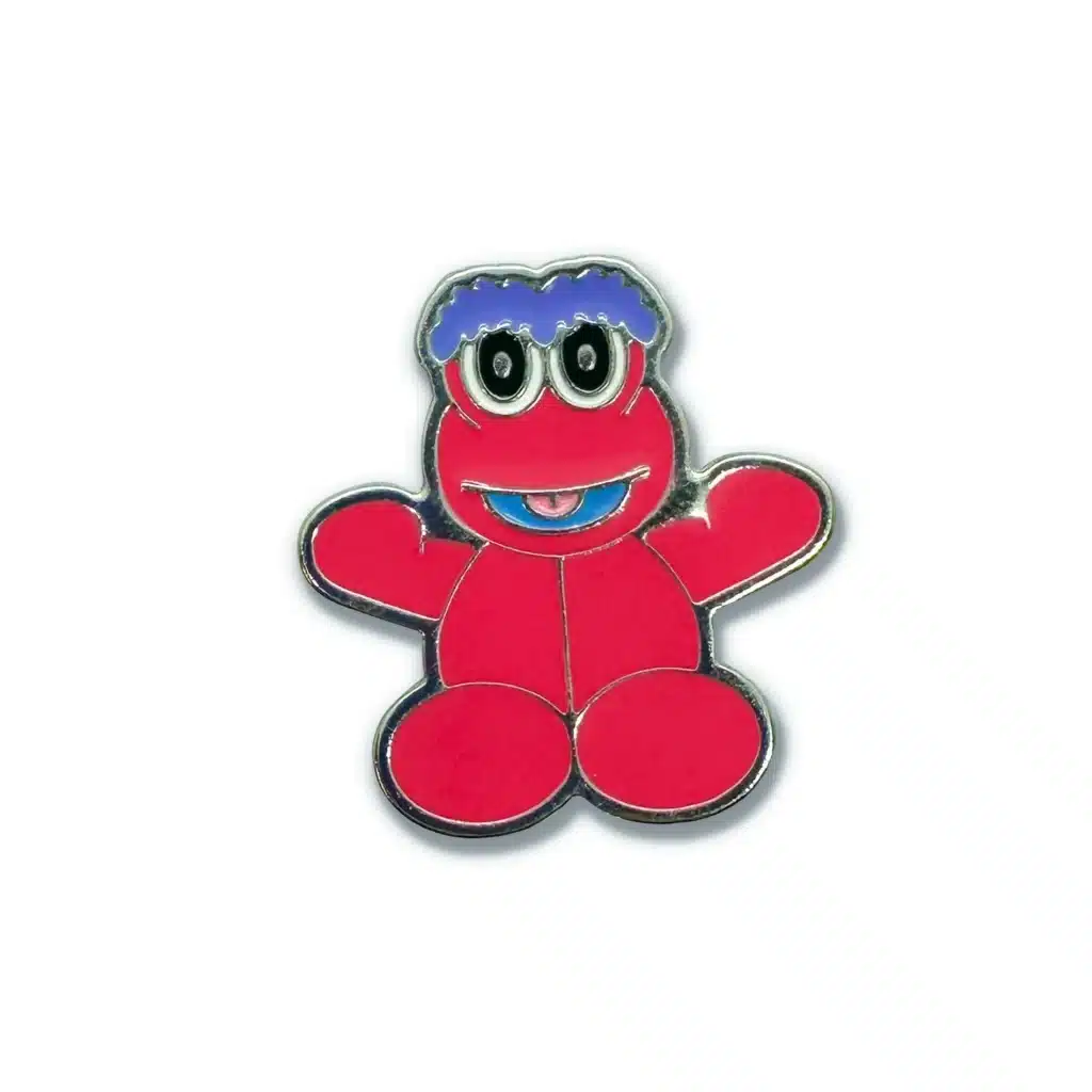 Pin do personagem Melocoton, em metal, com 3cm de altura e fecho de silicone, exibindo um design colorido e amigável.