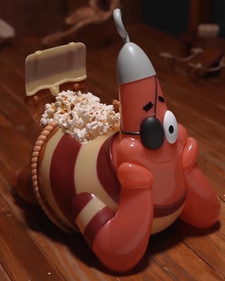 Balde de pipoca em formato do personagem Patrick Estrela, com pipoca na parte de cima e iluminação em LED interna, deitado com as mãos nas bochechas.