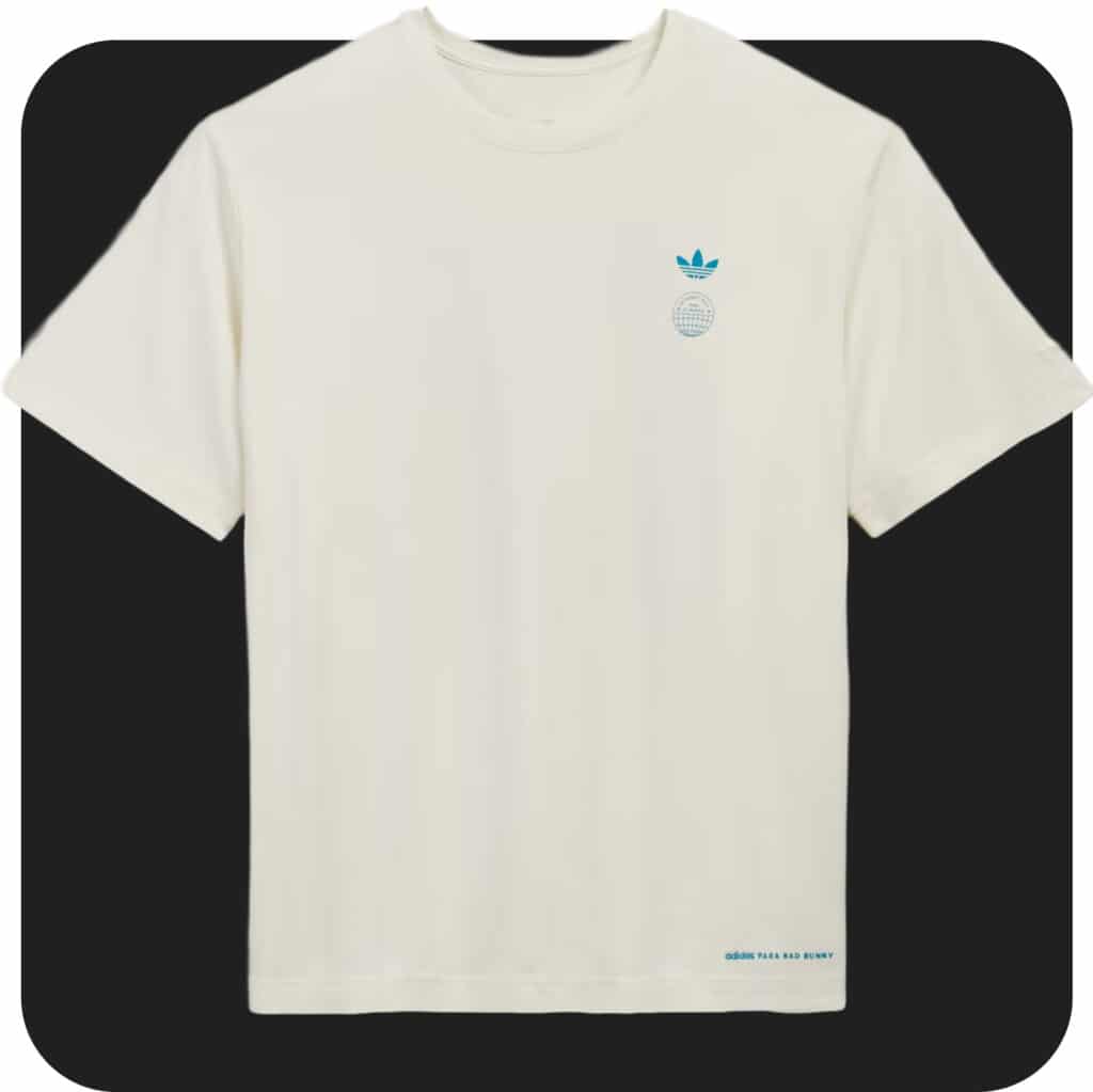 Camiseta cor creme com o logotipo azul da Adidas no lado esquerdo do peito e texto na barra inferior.