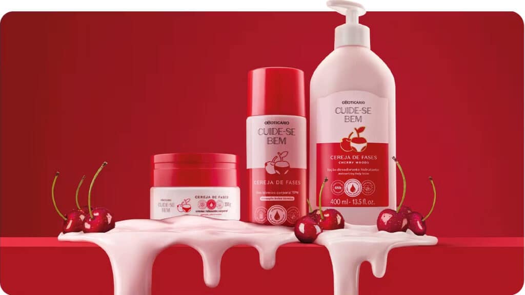Uma exposição de três produtos de cuidados com a pele da marca 'Cuide-se Bem', com embalagens temáticas de cereja, em um vibrante fundo vermelho. Os produtos incluem uma loção corporal, um creme hidratante e um desodorante, com cerejas em primeiro plano.