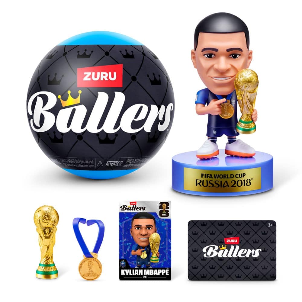Uma coleção de brinquedos com o tema da Copa do Mundo da FIFA, incluindo uma bola, uma estatueta de Kylian Mbappé segurando o troféu, uma medalha de brinquedo e embalagem com a marca ZURU Ballers.