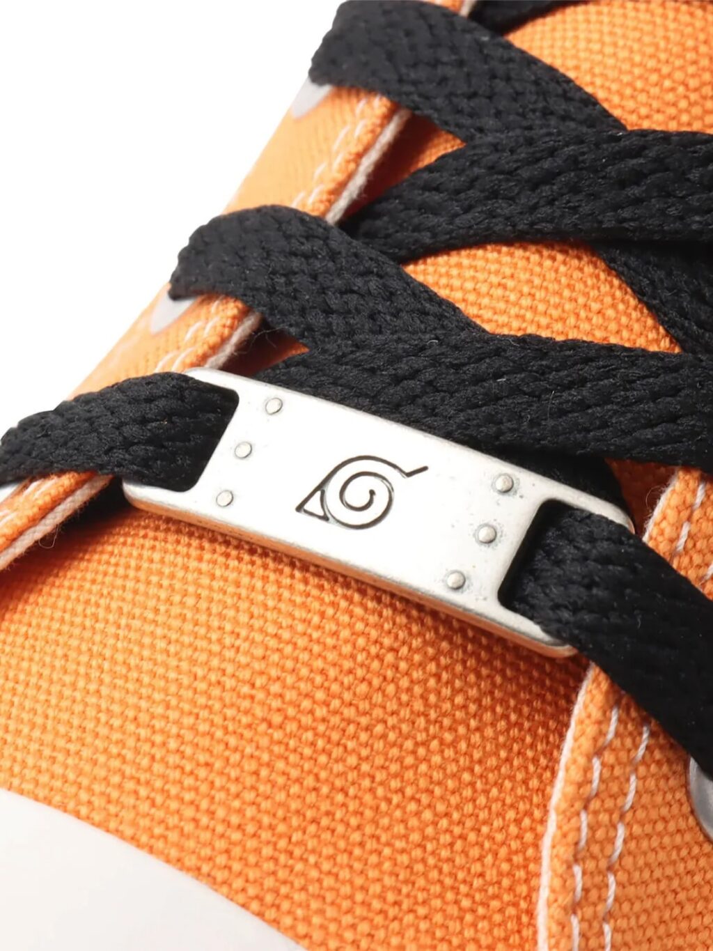 Detalhe de um tênis laranja com cadarços pretos e um fecho de metal com um logotipo em espiral.