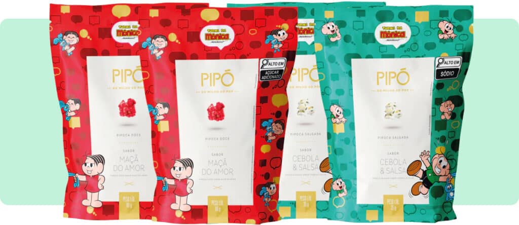 Quatro pacotes coloridos de pipoca Pipó, dois vermelhos com a etiqueta 'Maçã do Amor' e dois verdes com a etiqueta 'Cebola & Sal', com personagens de desenho animado na embalagem.