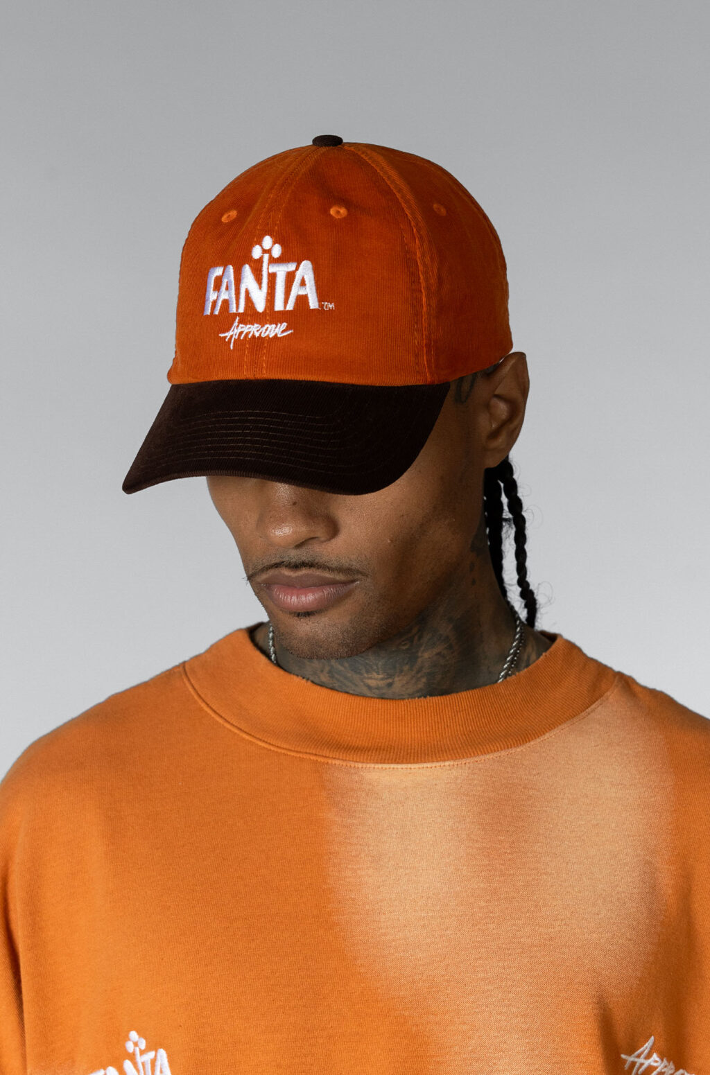 A person wearing an orange cap with the logo 'Fanta' and a matching orange shirt, showcasing a relaxed style.