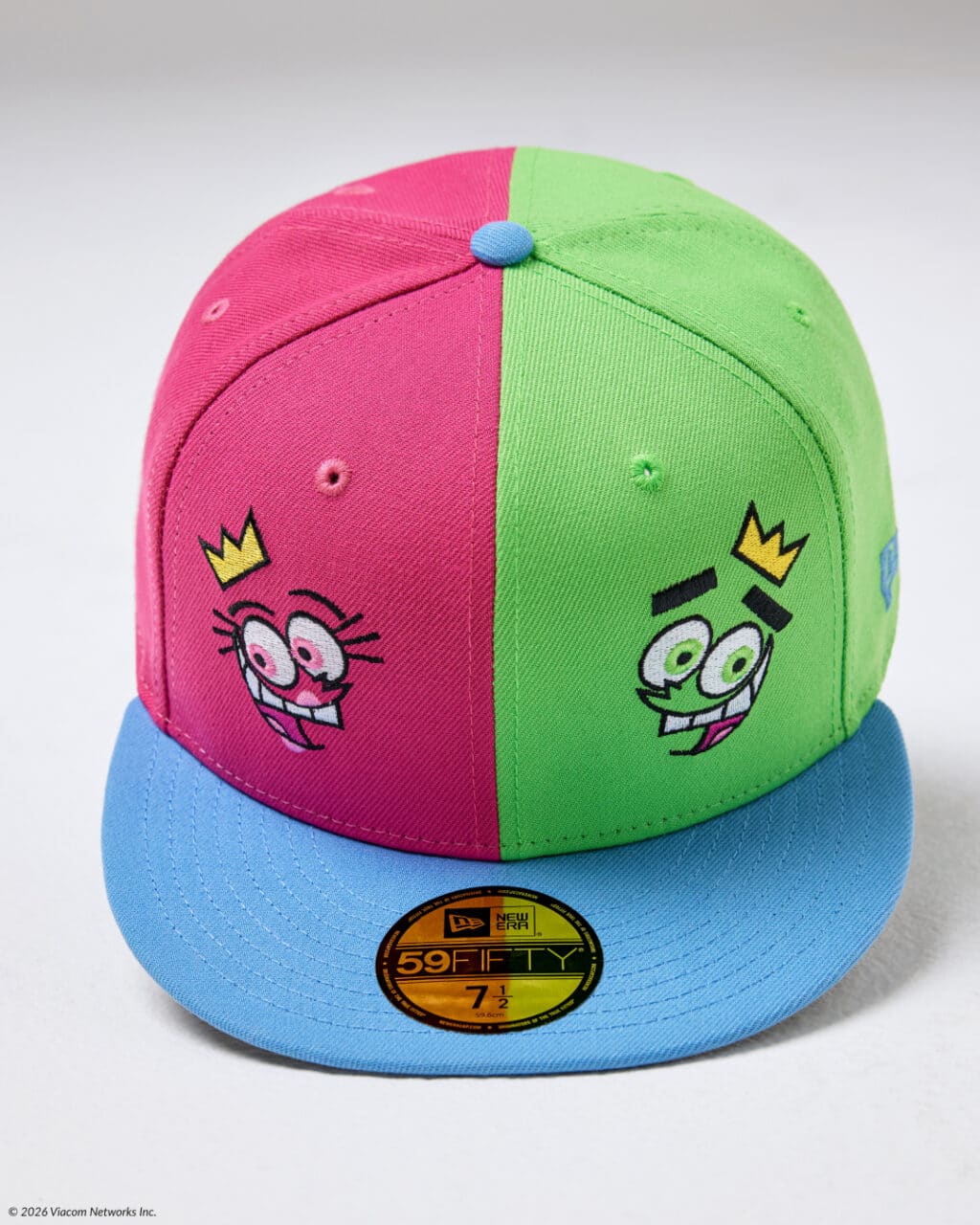 A colorful cap featuring a split design with pink and green panels, embellished with cartoon character faces and a blue brim.
