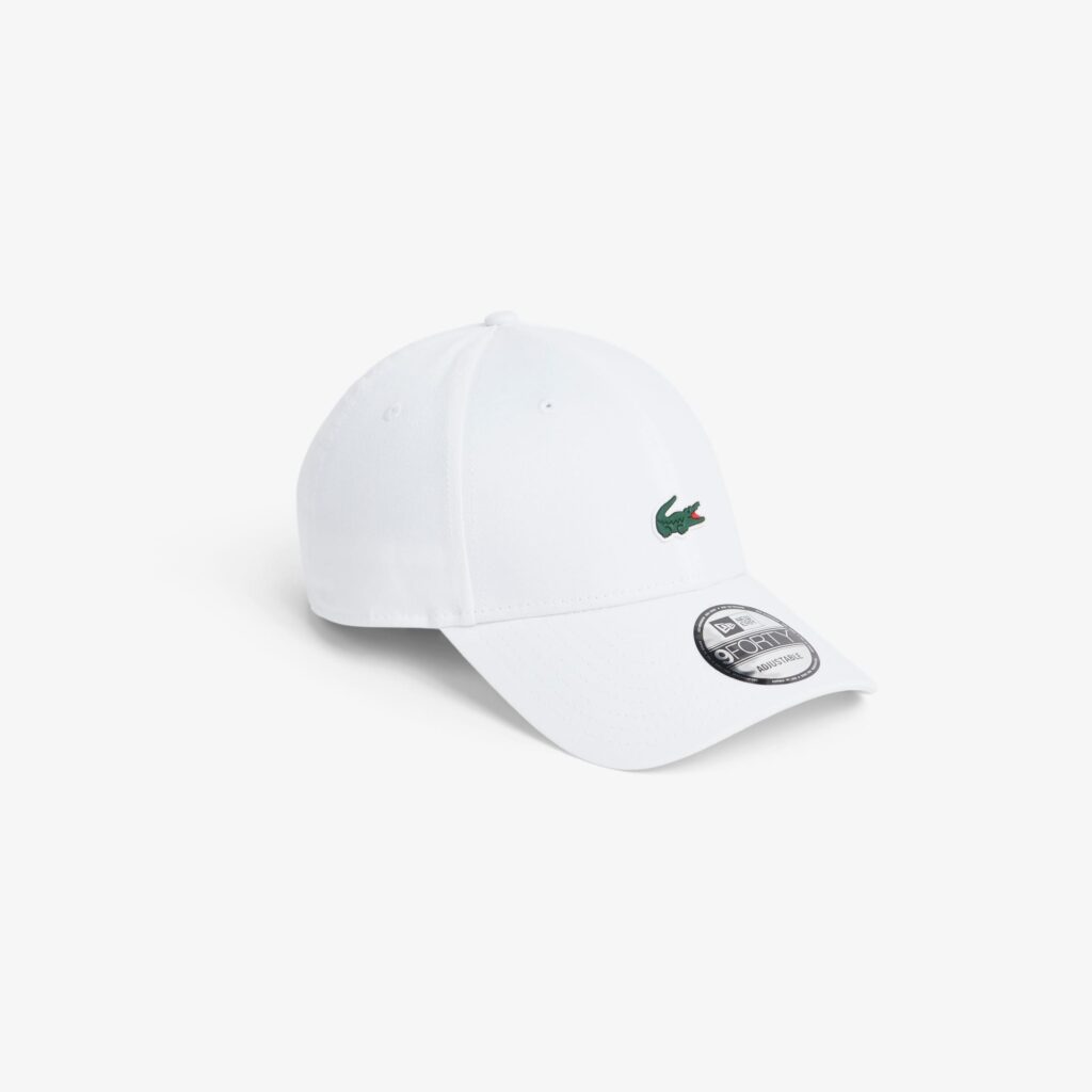 White baseball cap with a green Lacoste crocodile logo on the front.