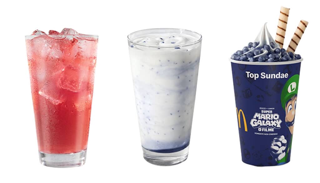 Um copo de bebida vermelha com gelo, um copo transparente com uma bebida branca com pedaços e um copo de sundae decorado com canudinhos e cobertura roxa.