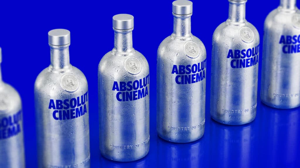 Diversas garrafas prateadas com o rótulo 'ABSOLUT CINEMA' sobre fundo azul.