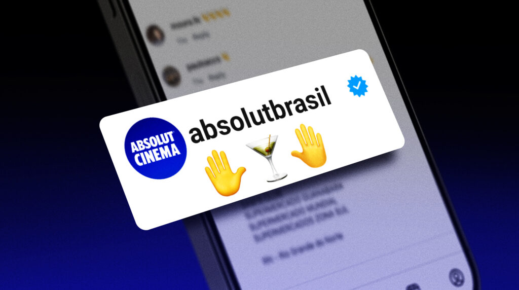 Um smartphone exibindo uma publicação em uma rede social com o nome de usuário 'absolutbrasil', o logotipo 'ABSOLUT CINEMA' e emojis de um coquetel e uma mão acenando.