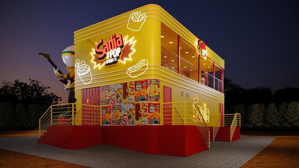 Restaurante de fast food bem iluminado chamado 'Sadia Pop', com fachada amarela e sinalização colorida, com escadas que levam a uma varanda e um personagem de desenho animado segurando um violão em primeiro plano.