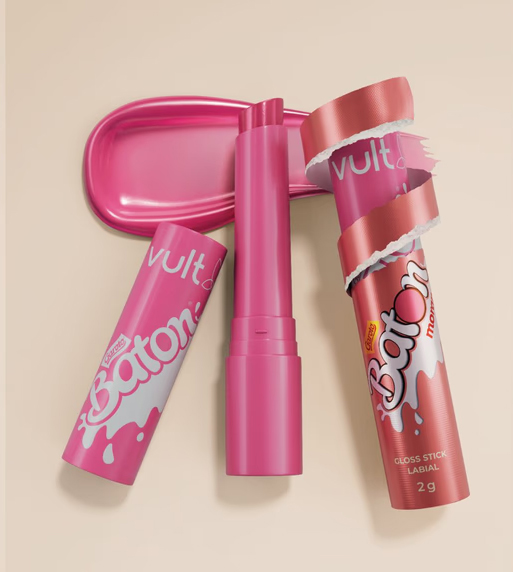 Uma coleção de produtos labiais rosa, incluindo um tubo de gloss labial 'Baton', um tubo de gloss sem embalagem e uma bandeja rosa.