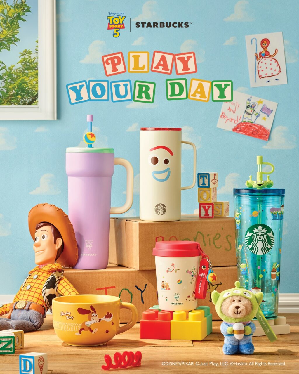 A vibrant display of Toy Story 4 merchandise and Starbucks cups. Featured items include a purple tumbler, a white cup with a smiley face, a red Starbucks cup with cartoon designs, along with plush toys like Woody and a green alien character. The background has playful colors and decorative elements, creating a whimsical atmosphere.