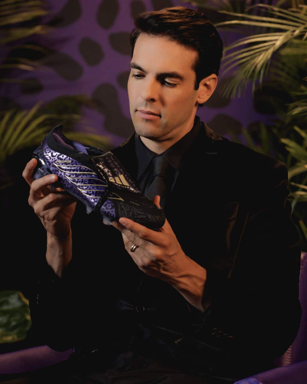 Kaká posa segurando uma chuteira adidas Predator Kaká Signature em cenário com estampa de folhas