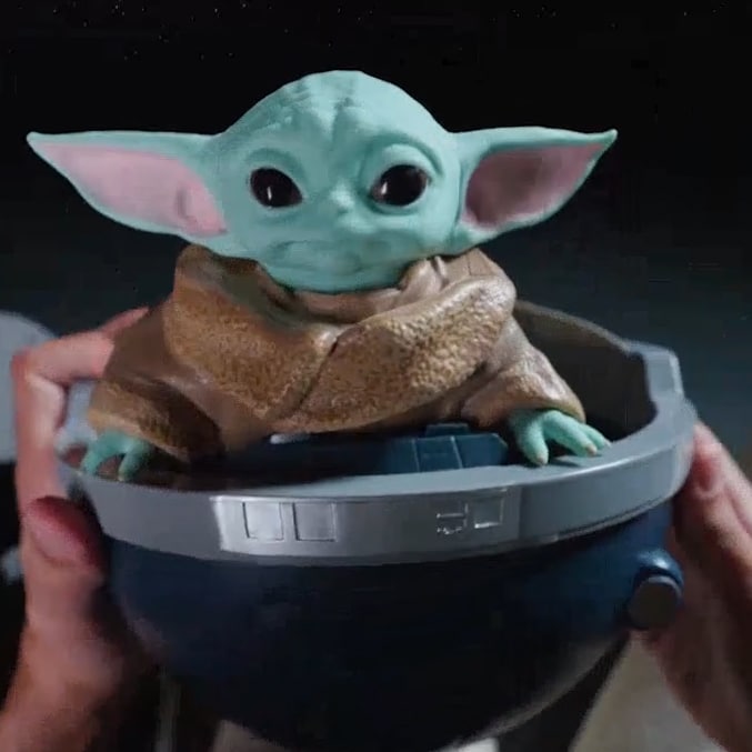 Balde de pipoca da Cinemark com Grogu, personagem de Star Wars, segurado por mãos.