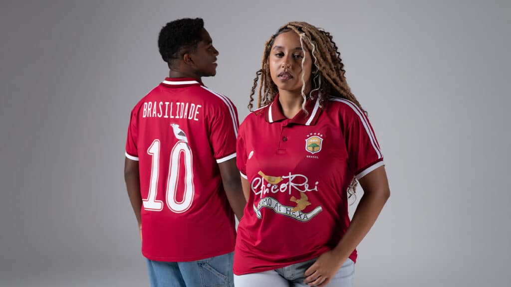 Dois modelos com camisa vermelha do Chico Rei, uma com “BRASILIDADE” e “10” nas costas, em estúdio