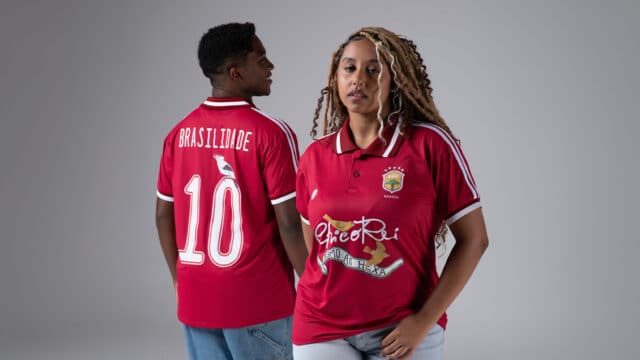 Dois modelos com camisa vermelha do Chico Rei, uma com “BRASILIDADE” e “10” nas costas, em estúdio