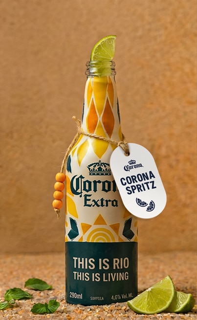 Garrafa de alumínio da Corona Extra com rótulo “Corona Spritz” e tag “THIS IS RIO” sobre fundo bege