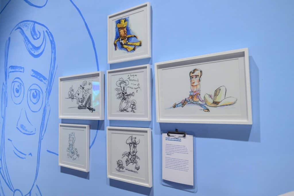 Uma colagem de esboços de personagens emoldurados em uma parede azul clara, apresentando vários personagens animados e uma prancheta com uma descrição em texto.