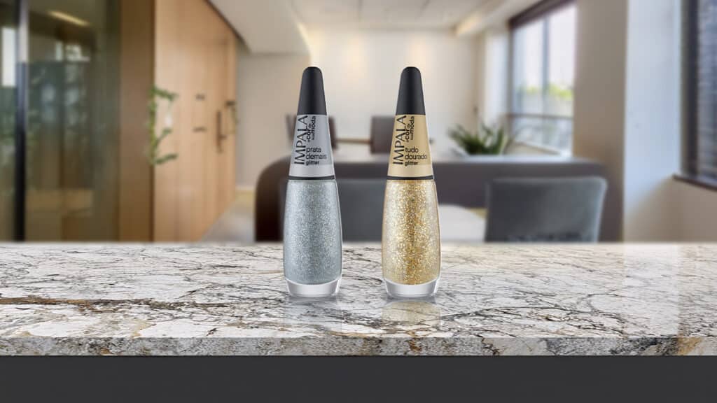 Dois esmaltes Impala cromados glitter em tons prata e dourado sobre uma bancada clara.