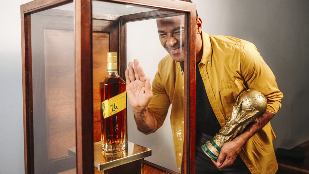 Johnnie Walker em edição para a Copa do Mundo, com garrafa e Cafu acenando em frente a uma vitrine de madeira