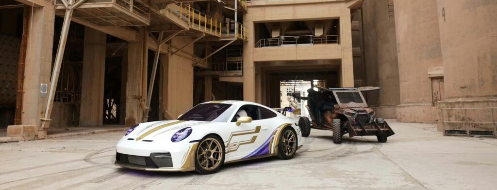 Carro esportivo Porsche branco com detalhes azuis em cenário urbano, ao lado de um veículo de apoio, em imagem promocional
