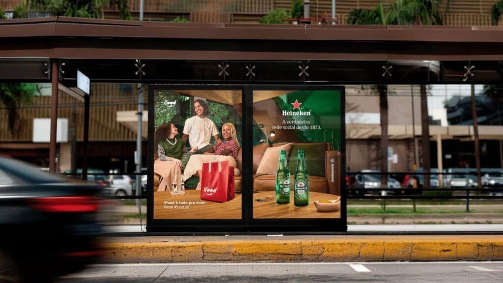 Painel publicitário Heineken em ponto de ônibus mostrando pessoas socializando e garrafas da marca
