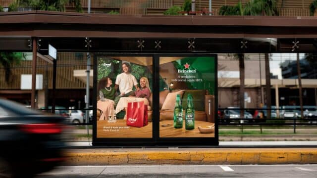 Painel publicitário Heineken em ponto de ônibus mostrando pessoas socializando e garrafas da marca