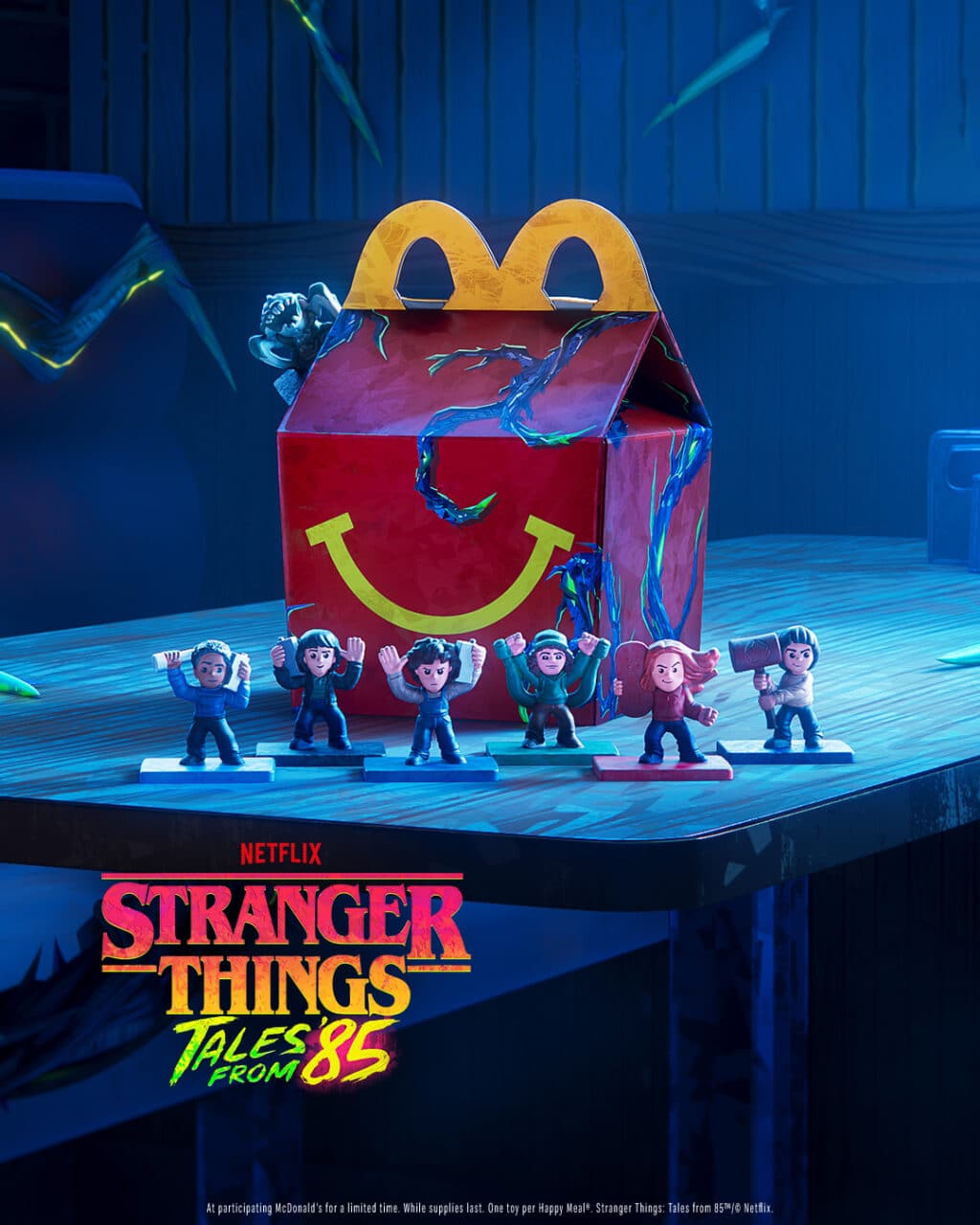 Embalagem do McDonald’s com personagens e logotipo de Stranger Things Tales from 85, em cenário azul da colaboração com a Netflix.