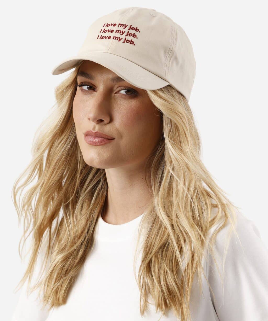 Modelo usando boné bege com estampa “I love my job” inspirada em O Diabo Veste Prada da C&A.