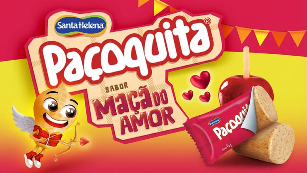 Paçoquita Maçã do Amor Imagem da Paçoquita Maçã do Amor com embalagem e ilustração em fundo festivo de São João.