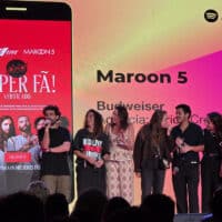 Equipe e convidados em palco com telão do show “Maroon 5” e cartaz promocional da Budweiser Super Fã.