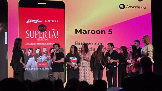 Equipe e convidados em palco com telão do show “Maroon 5” e cartaz promocional da Budweiser Super Fã.