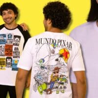 Três pessoas vestindo camisetas da exposição Mundo Pixar no Rio de Janeiro, com estampas de personagens e elementos icônicos.