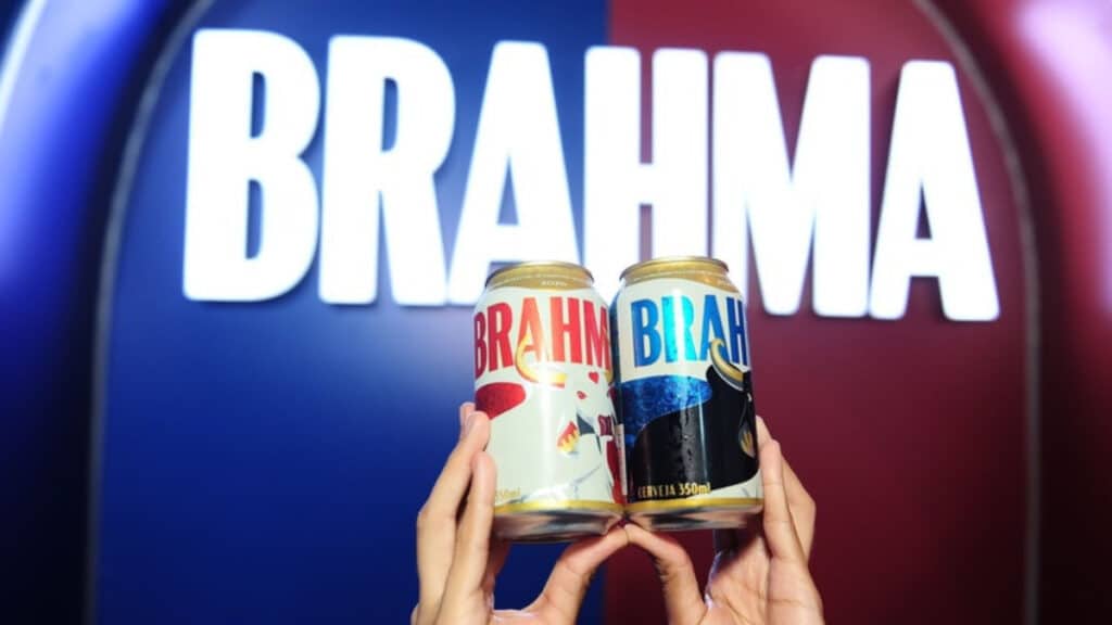 Pessoas exibem duas latas temáticas Brahma para o Festival de Parintins 2026, com fundo em azul e vermelho.