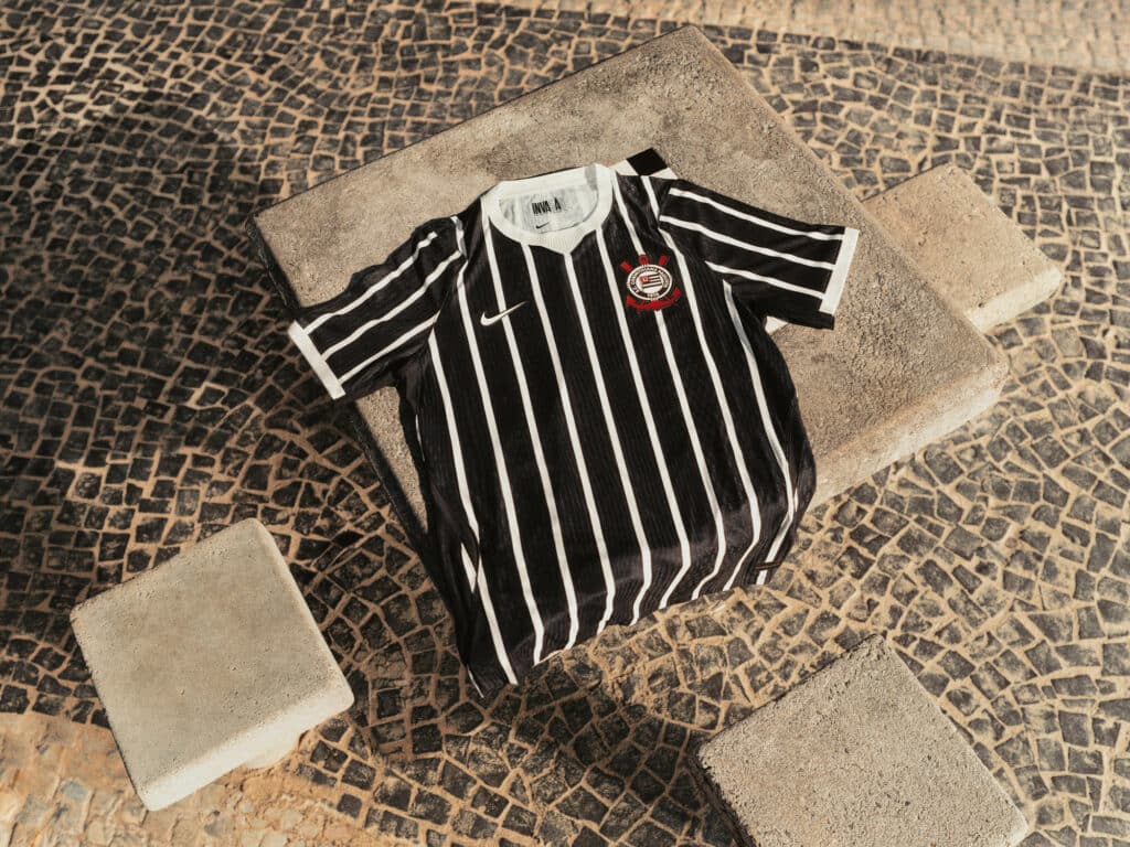 Camisa do Corinthians preta e branca listrada Nike em destaque sobre piso de pedra