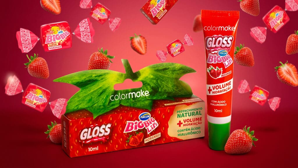 Embalagens de gloss Big Big Lips colorM ake e Arcor com morango, com ácido hialurônico e mentol sobre fundo vermelho