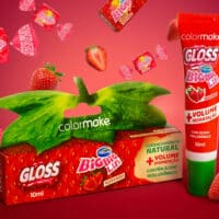 Embalagens de gloss Big Big Lips colorM ake e Arcor com morango, com ácido hialurônico e mentol sobre fundo vermelho