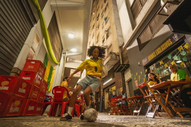 Campanha Brahma para a Copa do Mundo, com jogador em campo e torcedores em cenário urbano