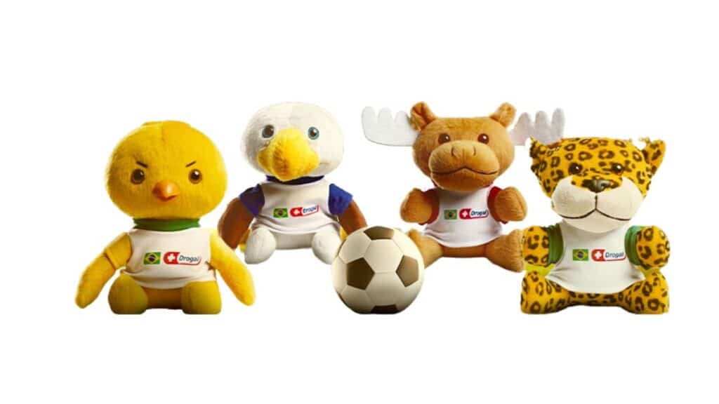 Pelúcias colecionáveis da Drogal inspiradas em mascotes de futebol com bola, amarelo, branco, onça e urso sobre fundo branco.
