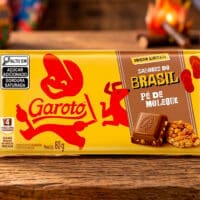 Embalagem do chocolate Garoto Pé de Moleque, edição Sabores do Brasil, com pedaços de amendoim na mesa ao fundo