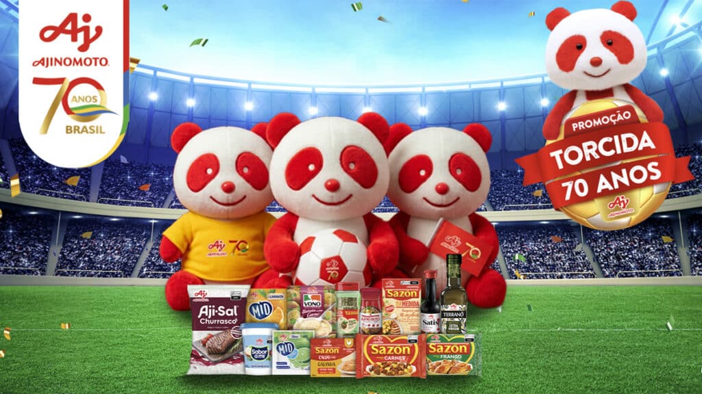 Aji-Panda e pelúcias Aji-Sol no gramado, com produtos Ajinomoto e banner de Promoção Torcida 70 anos.