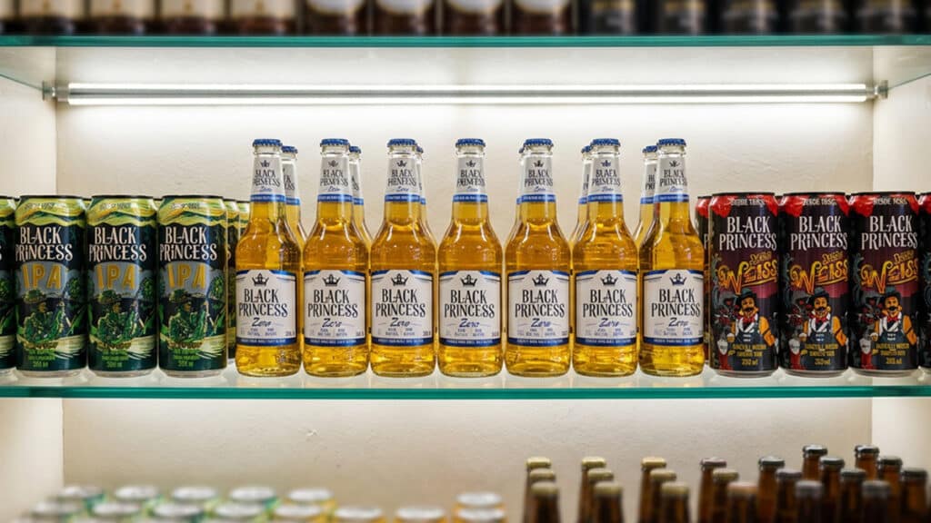 Cervejas Black Princess em lata e versões Zero e IPA Linha de cervejas Black Princess em garrafas e latas na prateleira, incluindo variações como IPA e Black Princess Zero.